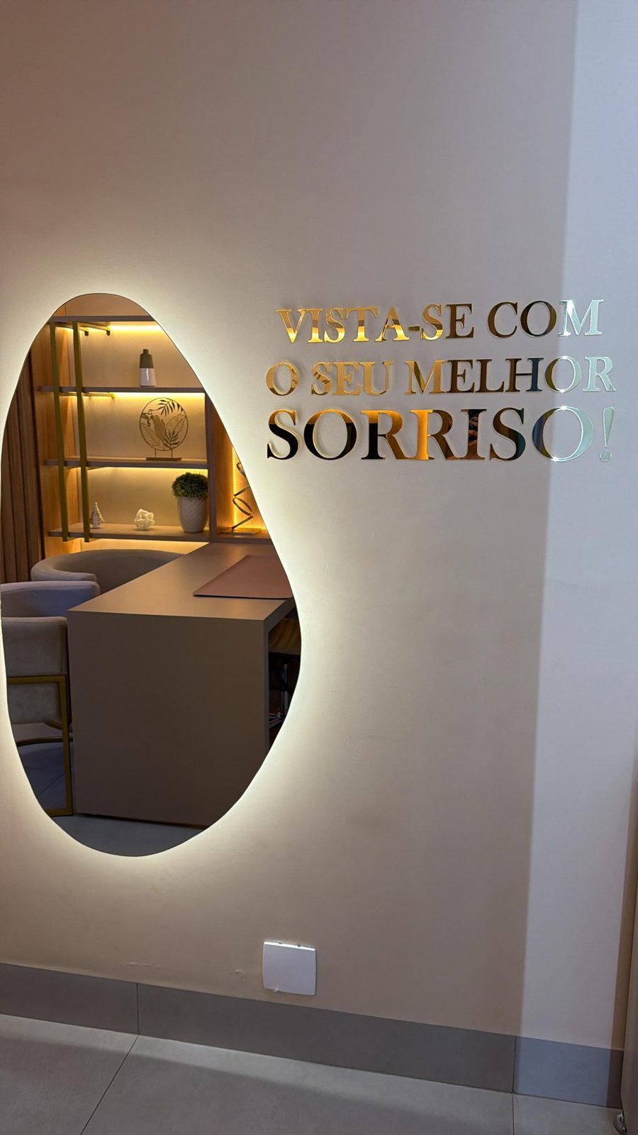 Espelho iluminado com a frase Vista-se com o seu melhor sorriso na parede do consultório