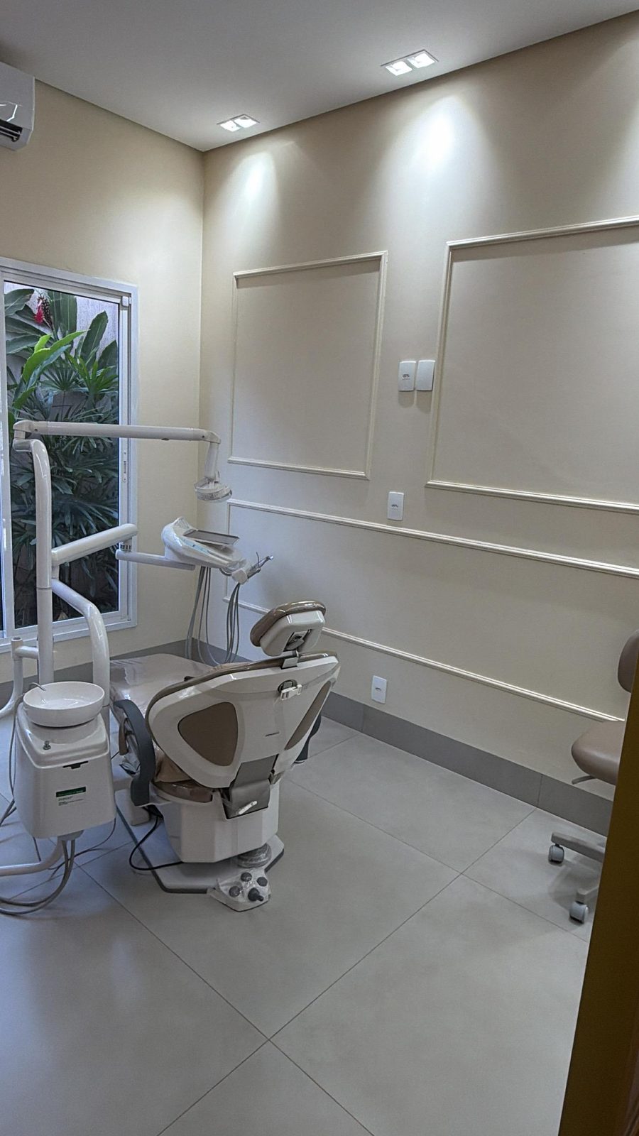 Sala clínica com molduras na parede e cadeira odontológica